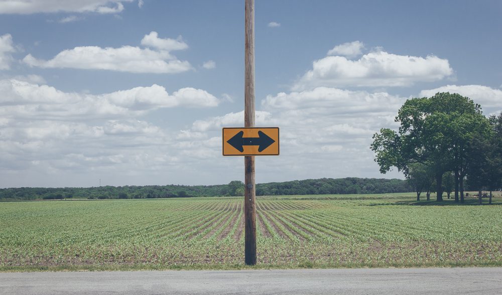 Cartel con flechas hacia dos direcciones en un camino rural